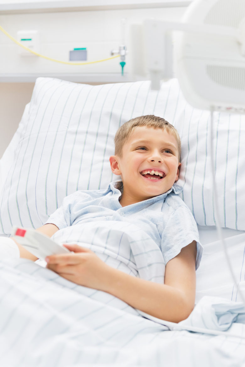 Boy with broken arm and cast playing in hospital on a modern tv set.