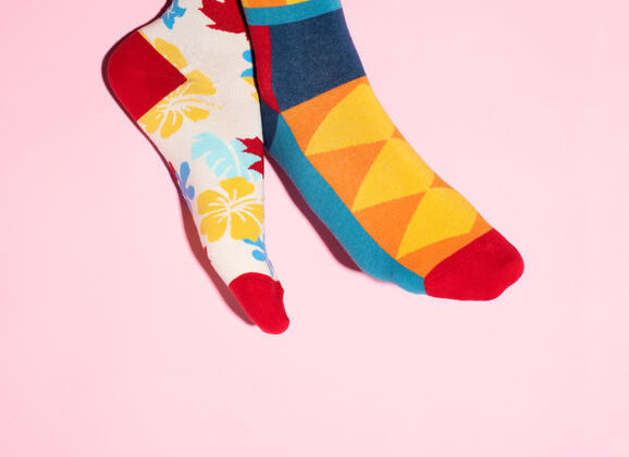 Relax feet wearing mismatched colorful socks against a pink background