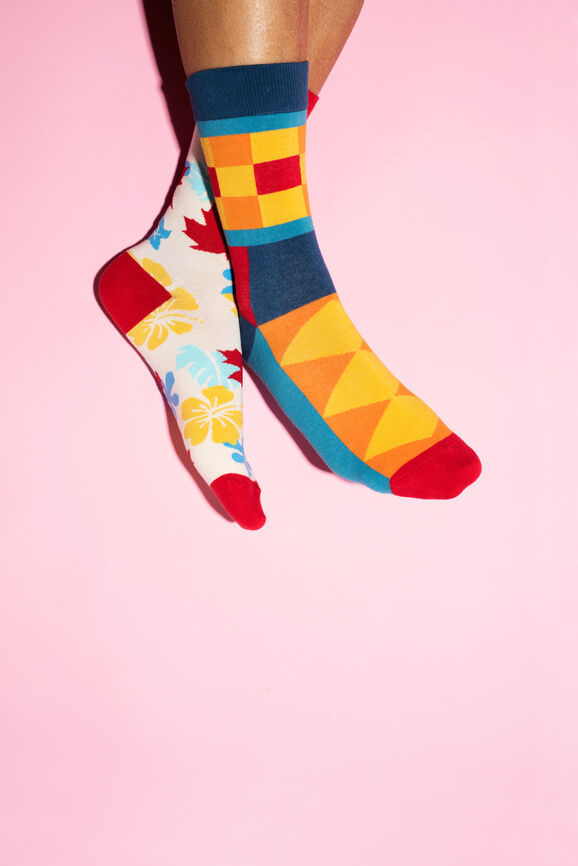 feet wearing mismatched colorful socks against a pink background