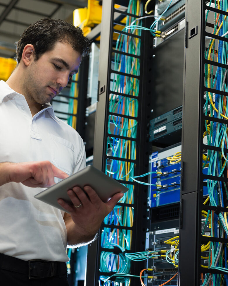 IT technician with network equipment and cables IT technician working on network servers and cables.