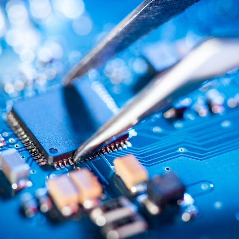 Electronic technician holding tweezers and assemblin a circuit board. Electronic technician holding tweezers and assemblin a circuit board.