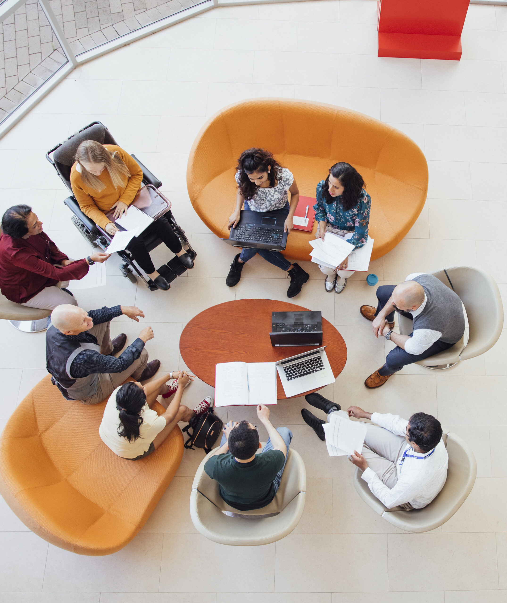 Diverse Group Discussion A birds-eye view of an academic group meeting in natural light with bright furniture.